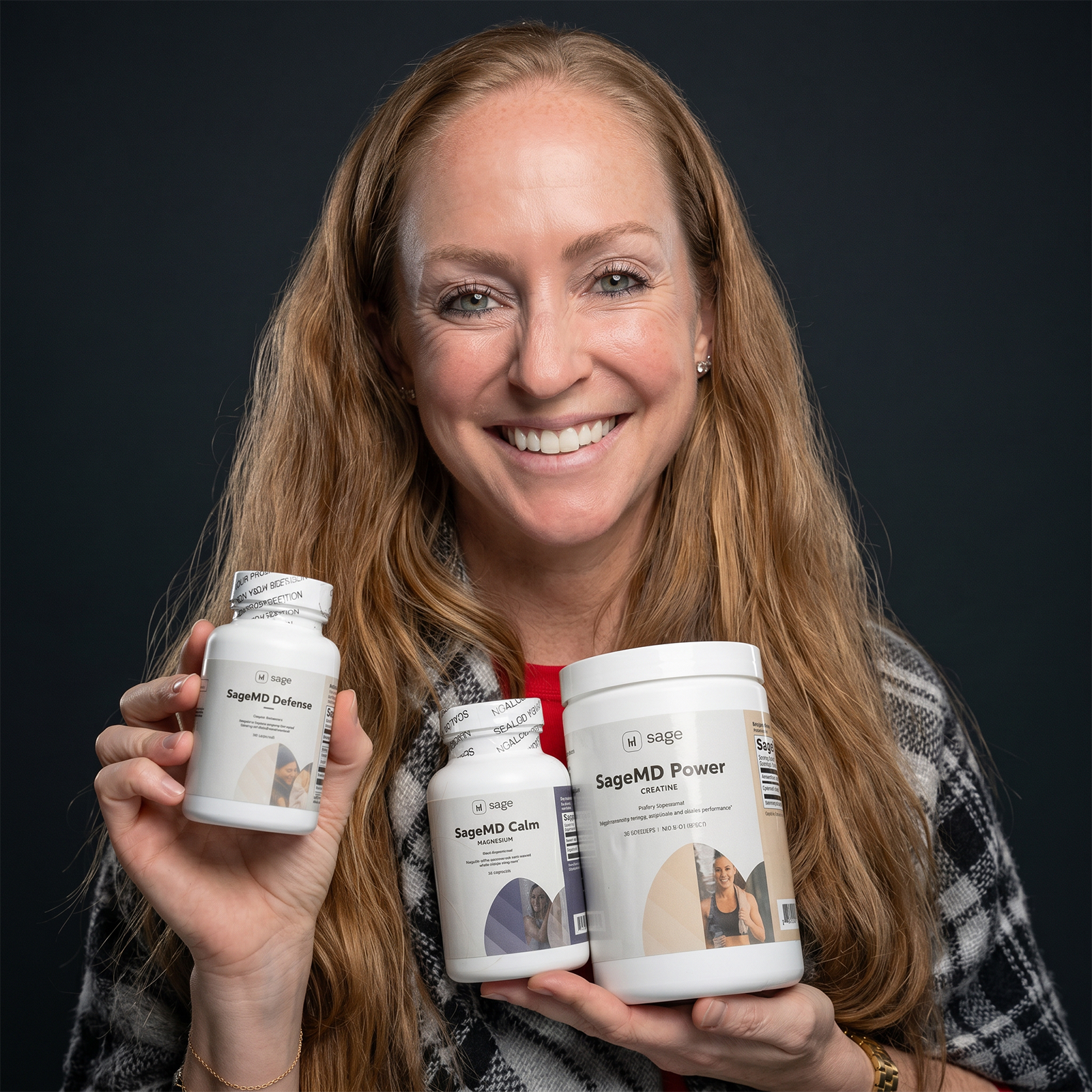 Woman holding three bottles of SageMD products against a black background
