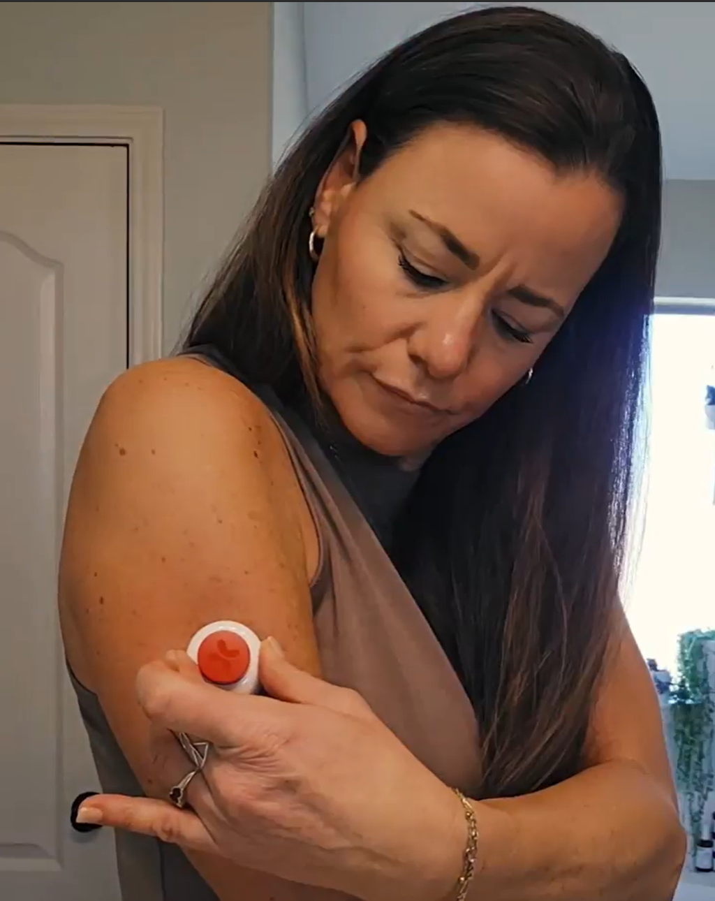 Woman applying the Tasso Blood Collection Device onto her upper arm.