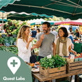 People shopping at an outdoor farmers market with a Quest Labs logo.