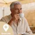 Man drinking from a white cup with a blurred background and Quest Labs logo.
