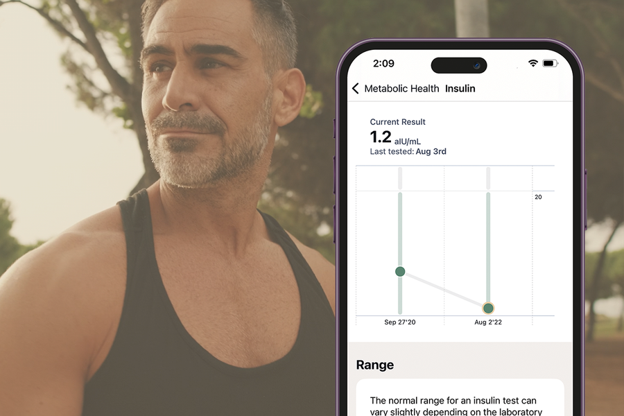 Man wearing a black tank top with a smartphone displaying Sage Health app showing Insulin Biomarker trend graph.