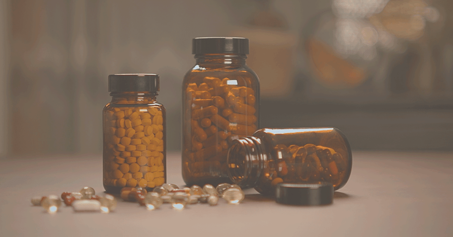 Three supplement bottles filled with pills on a blurred background
